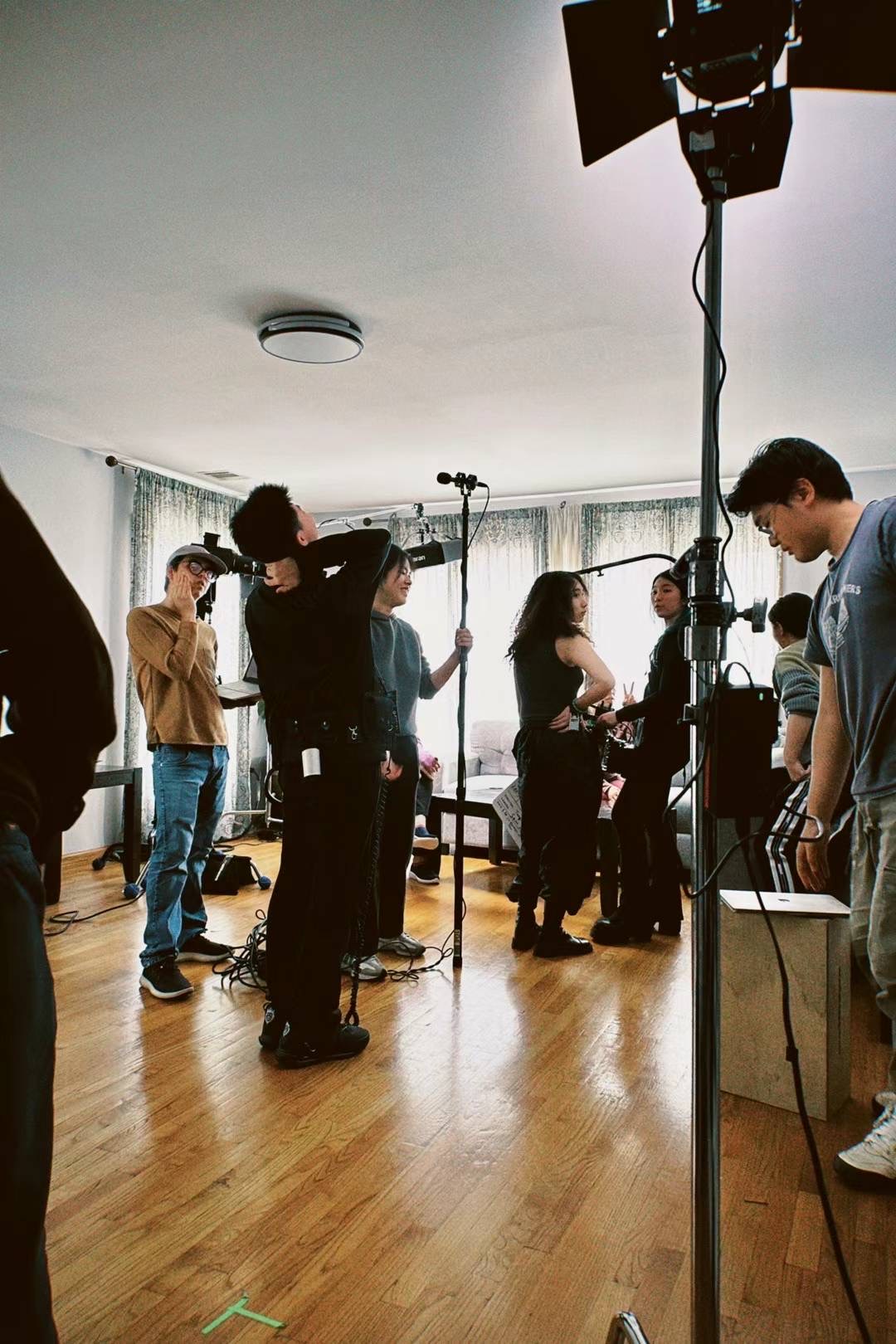 Behind the scenes of the Intermediate Narrative Production course. This is the set of the author’s film, “The Red Veil.” Student actors and a film crew stand in a living room.