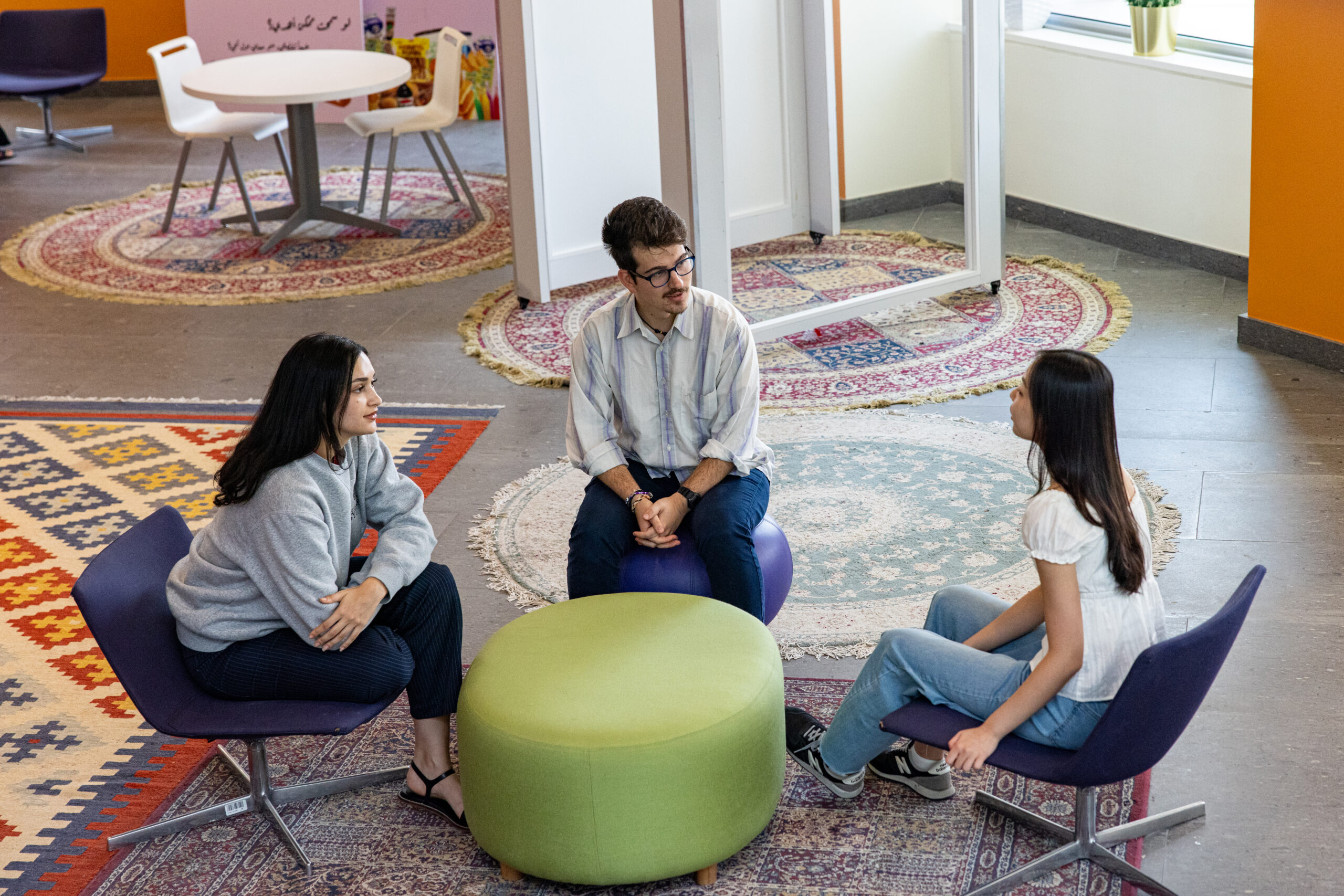 Stefan Mitikj and two other NYU Abu Dhabi students sitting together, engaged in conversation.