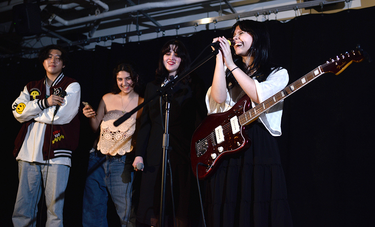 Four students performing on stage.