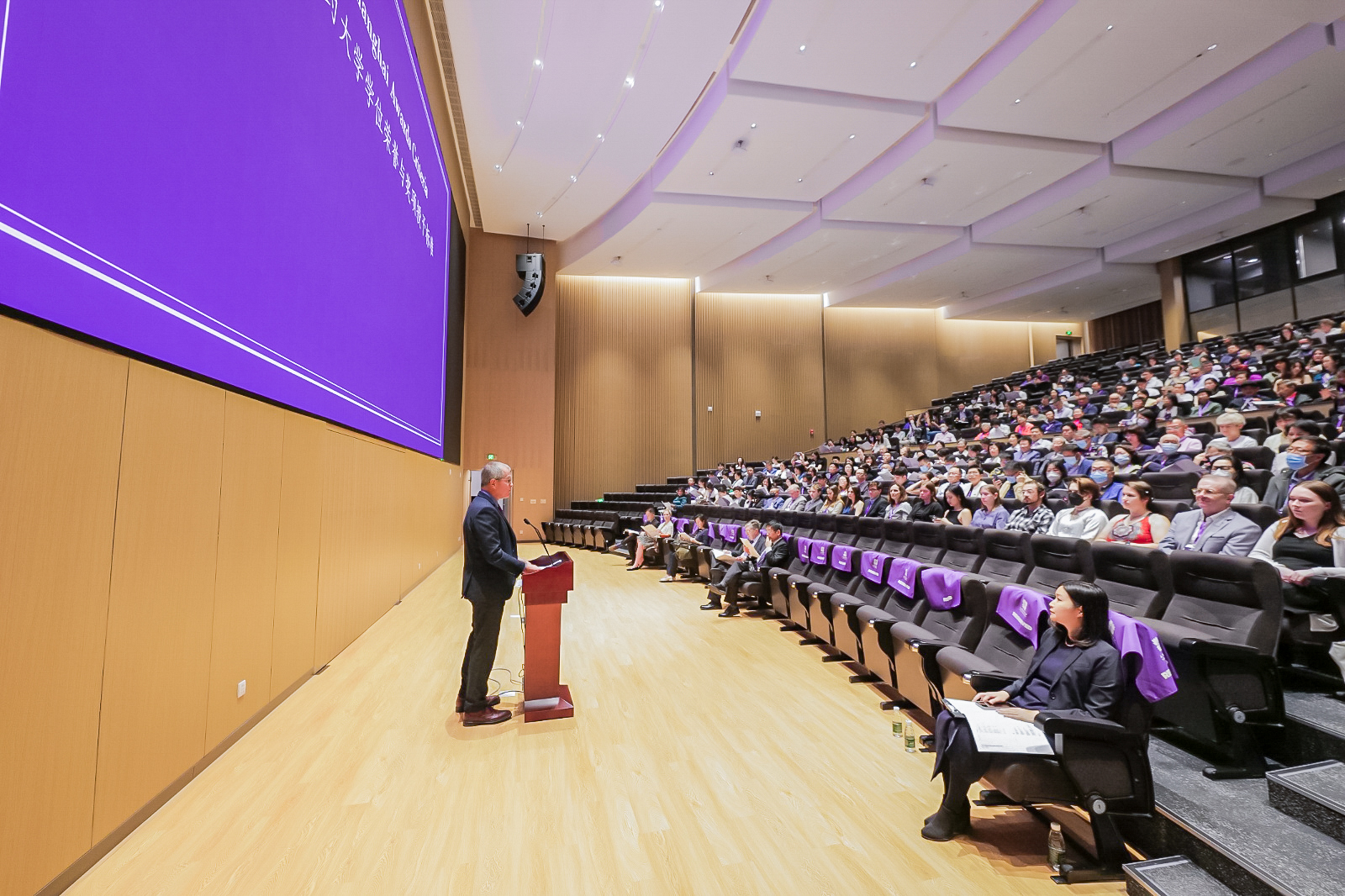 A speaker stands at the podium in the NYUSH Auditorium