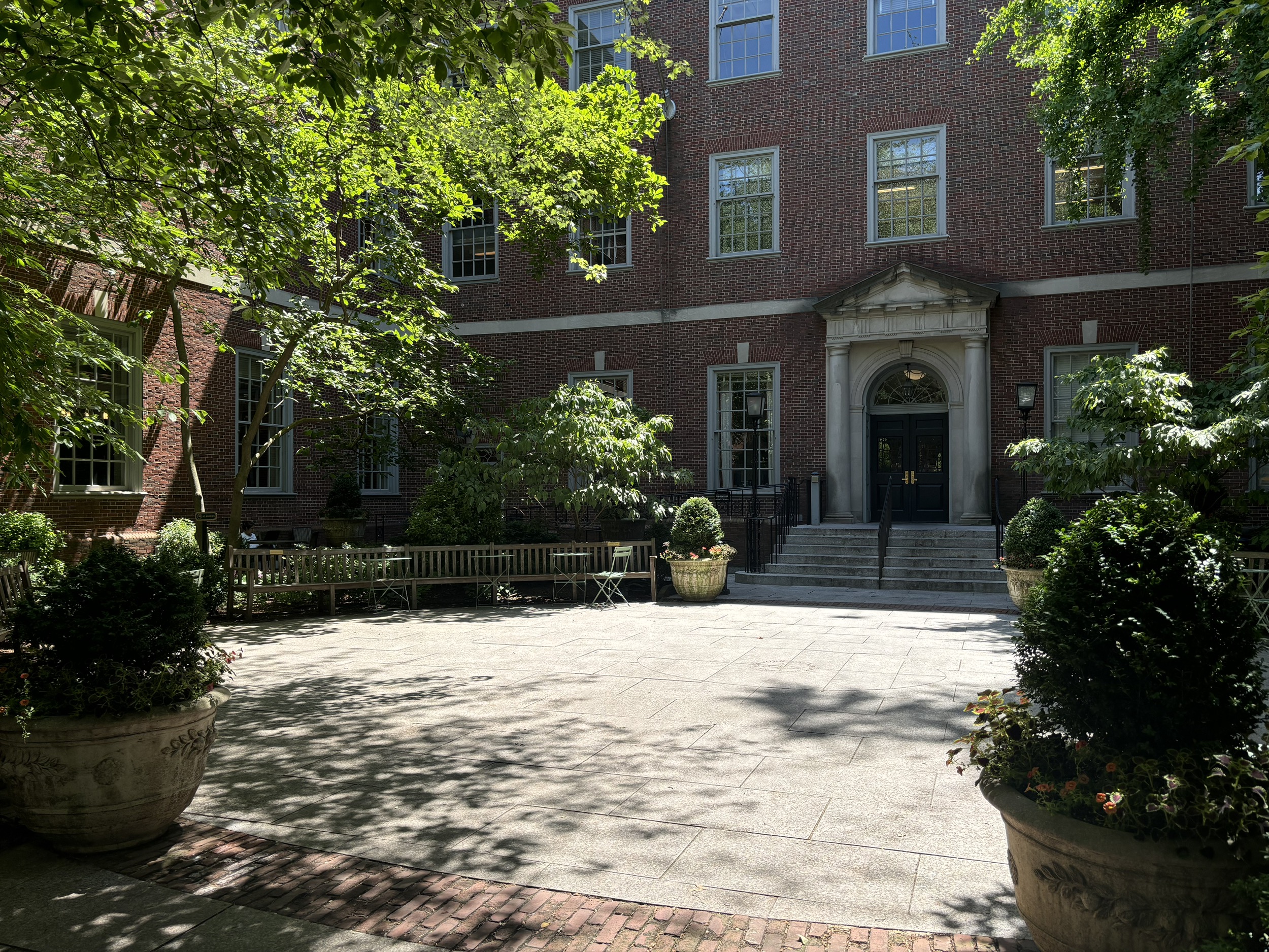 The courtyard of Vanderbilt Hall on a sunny day. The central area is surrounded by benches and trees.