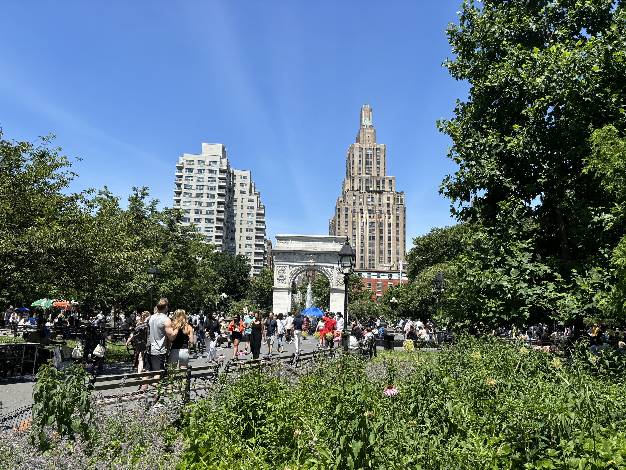 Washington Square Park on a summer day with clear blue skies and the arch in the distance