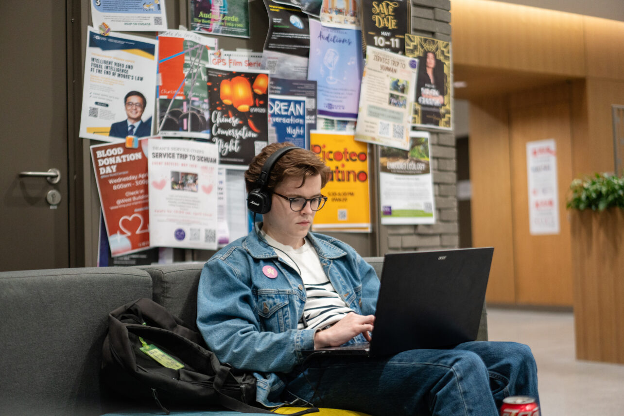 A student sits in front of a bulletin board full of flyers in Magnolia House