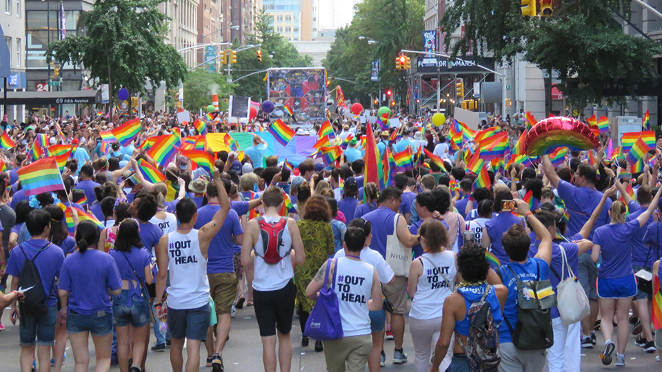 A group of NYU students wearing violet T-shirts walking in the NYC Pride March.
