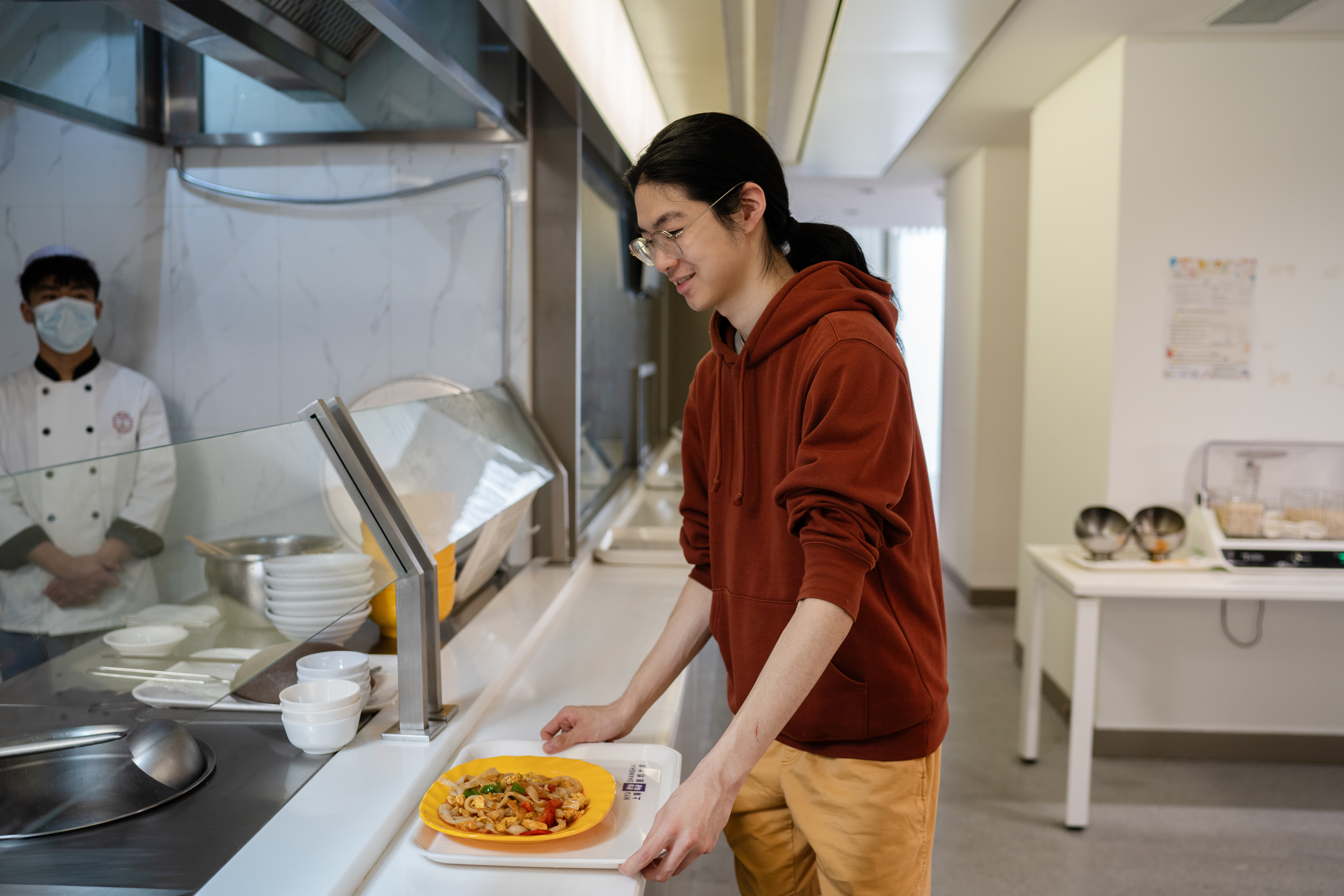 a student orders lunch at the NYUSH canteen