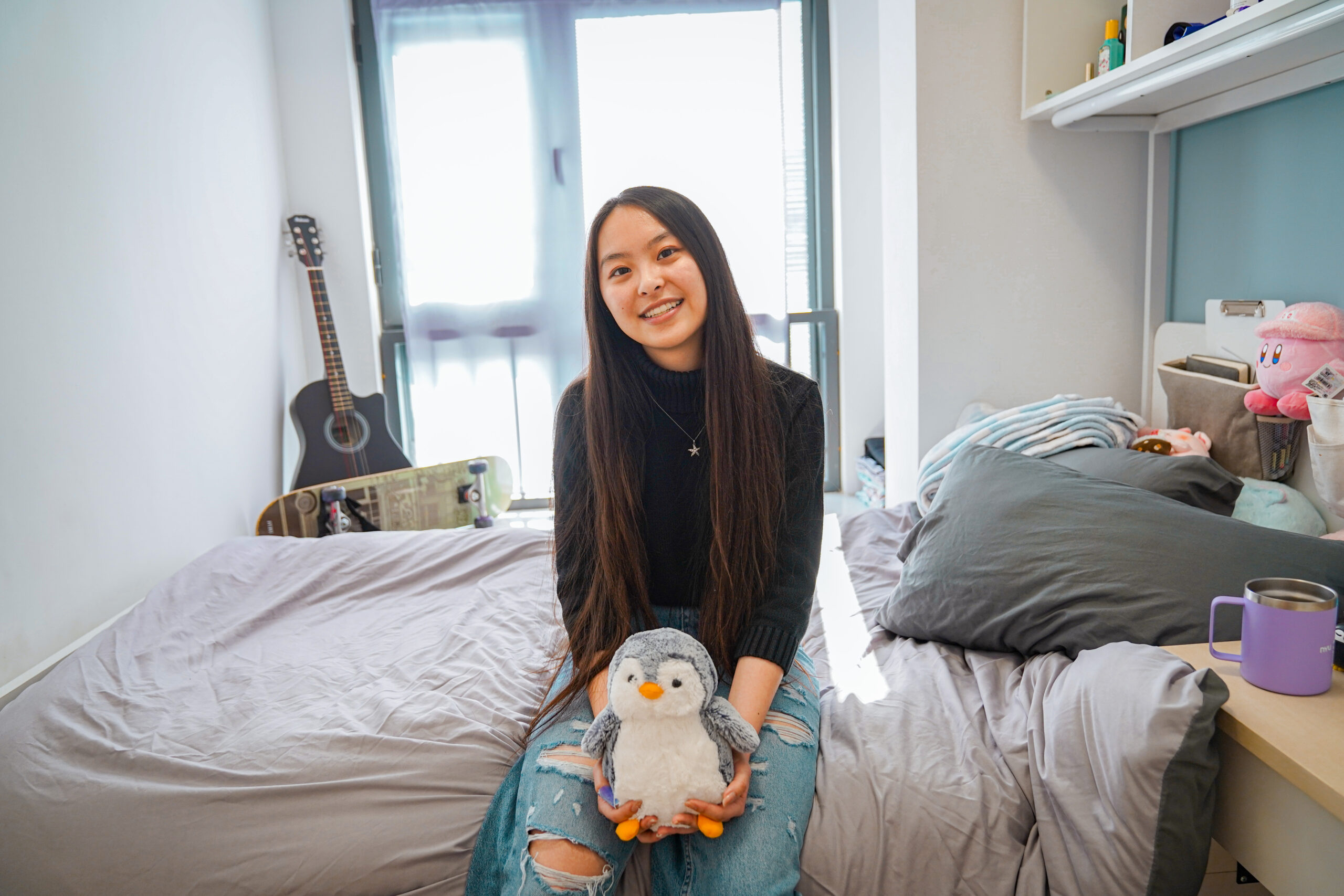 A student sits on their bed in a premium single room