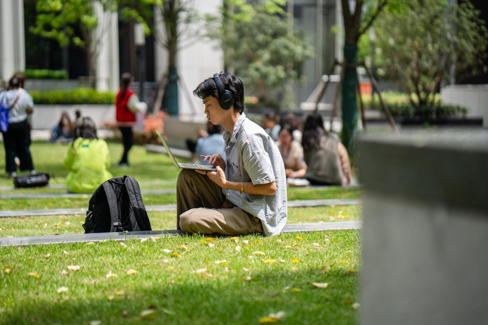 A student types at their computer on the campus courtyard