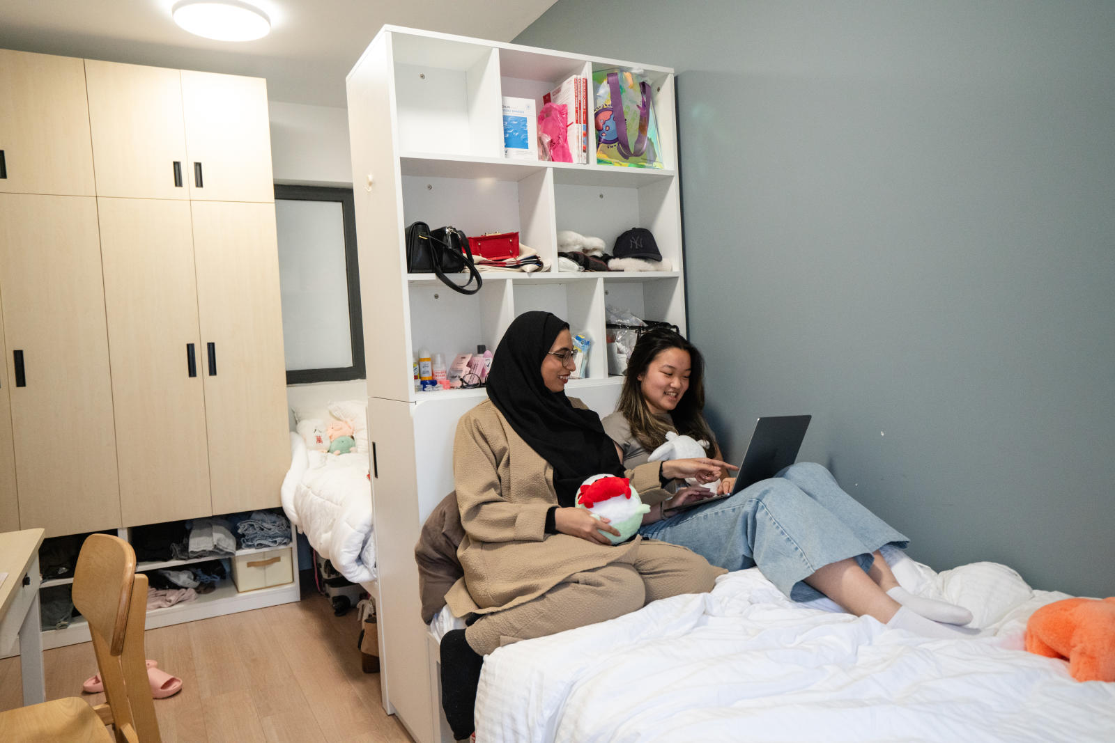 Two students study beside each other on a bed in the NYUSH residences