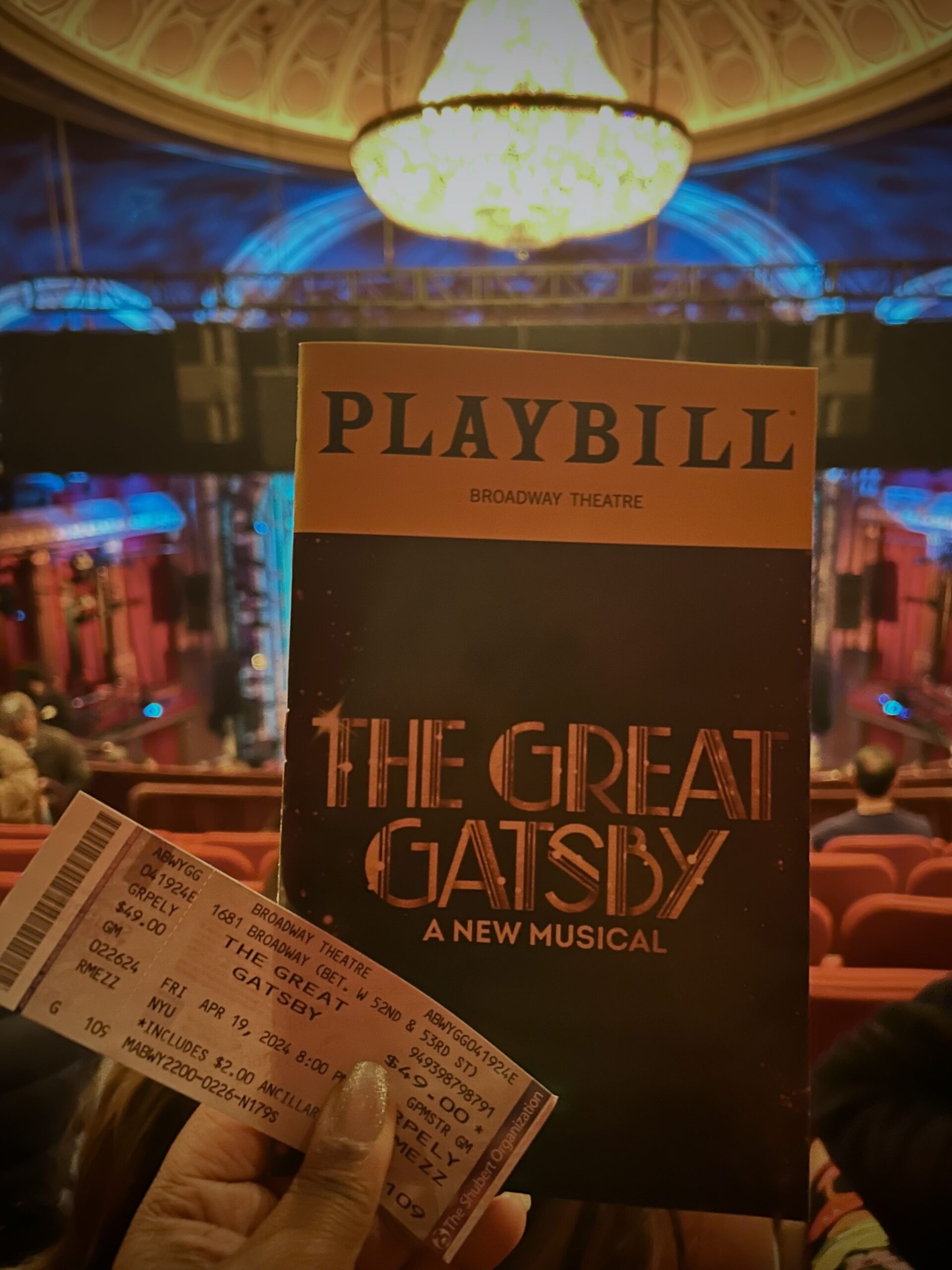 A playbill and tickets for The Great Gatsby with the stage out of focus in the background.