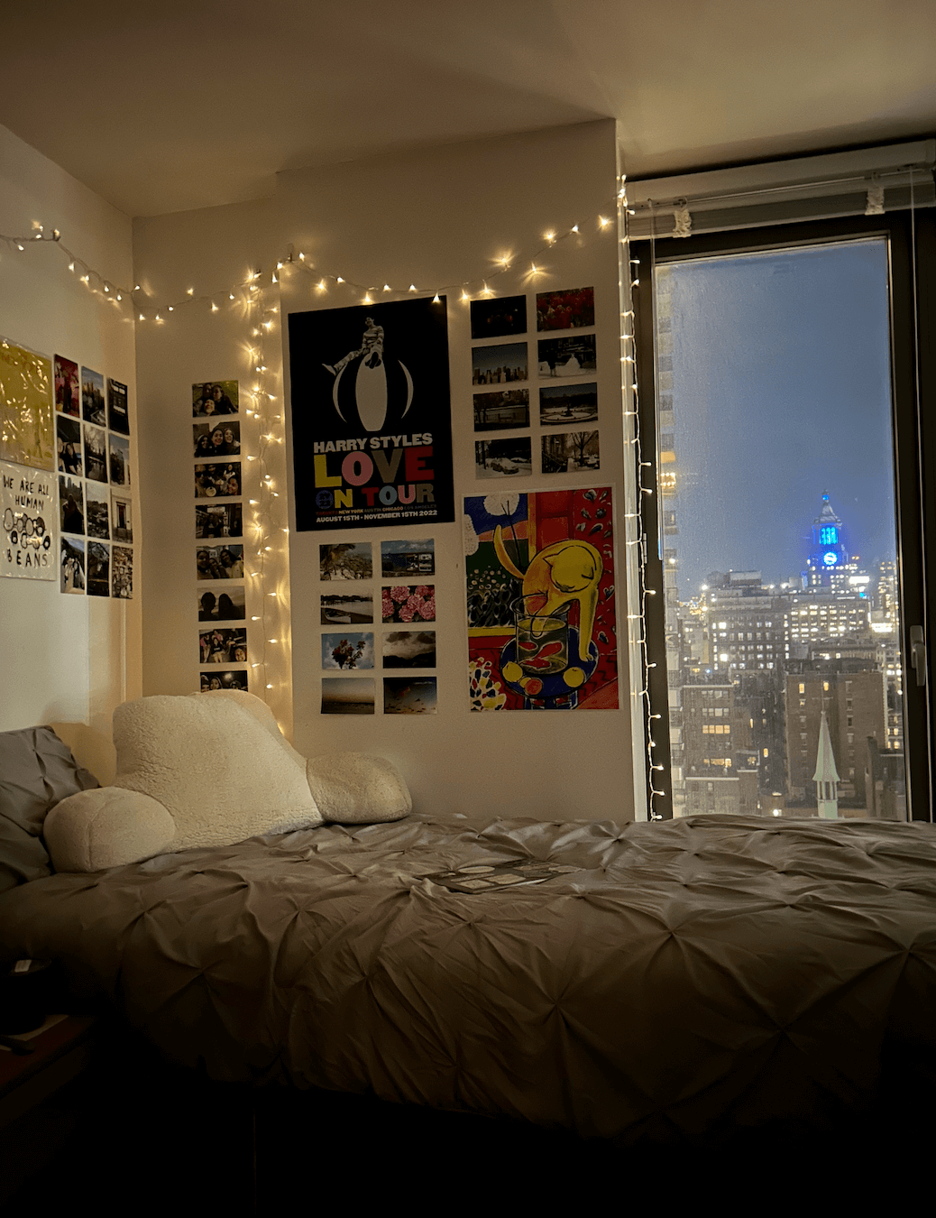 Bed in corner of a residence hall room with twinkle lights and photographs adorning the wall.