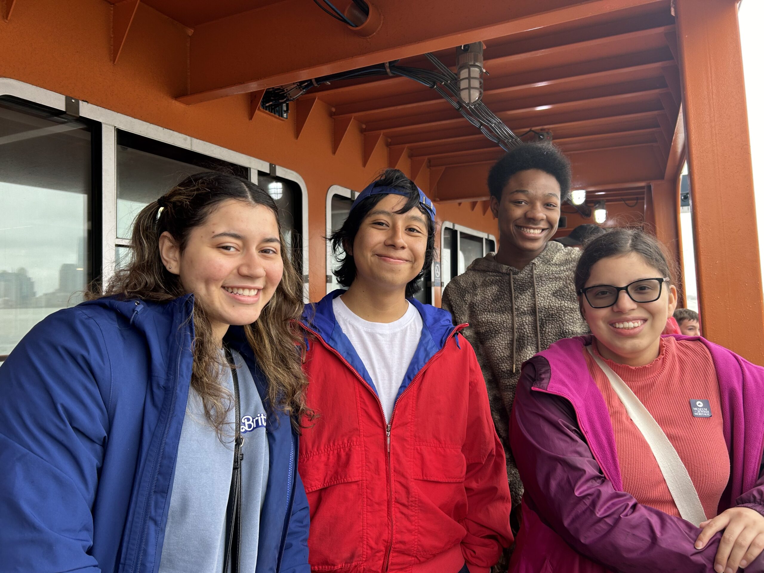 A group of four smiling for the camera during the Staten Island Ferry excrusion.