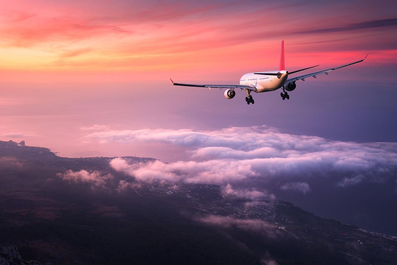 A plane flying in the air at sunset.