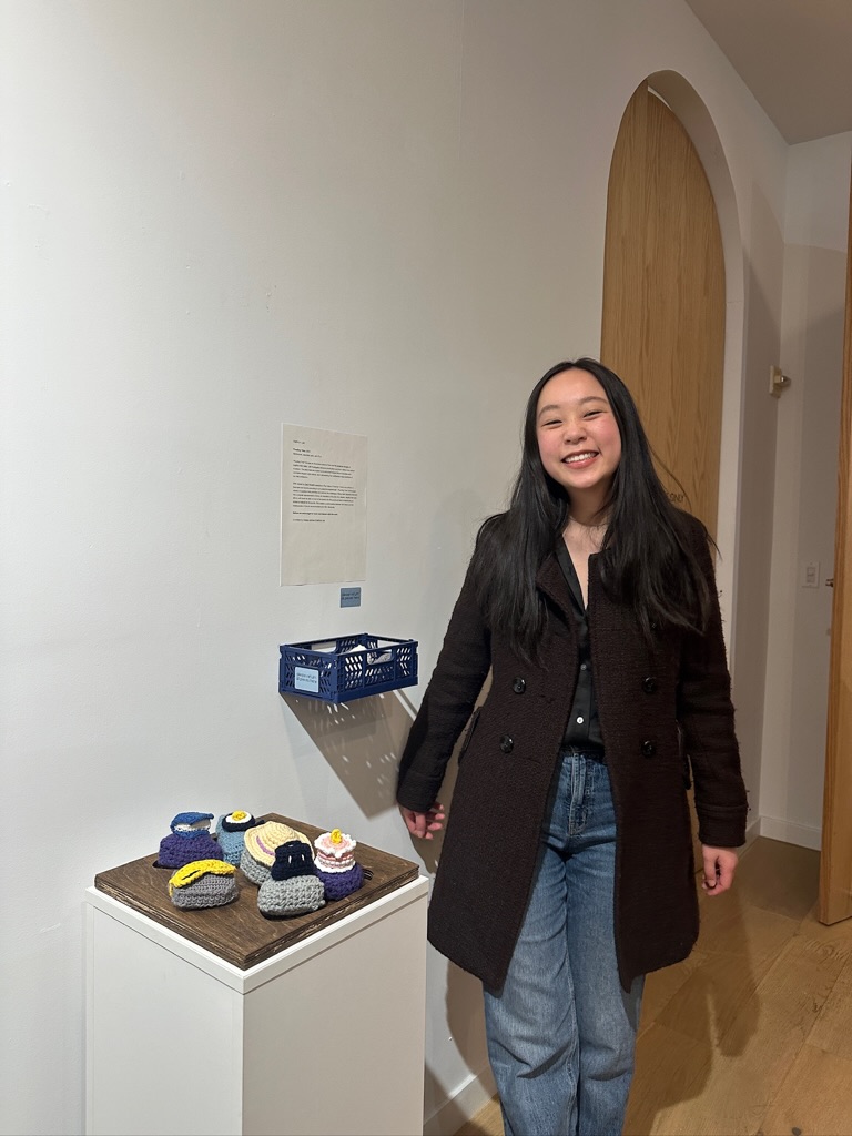 The author stands in front of her project exhibited at a gallery show.