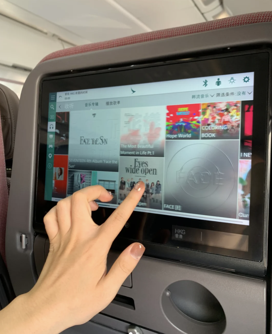 A person touches the in-flight entertainment system on an airplane.