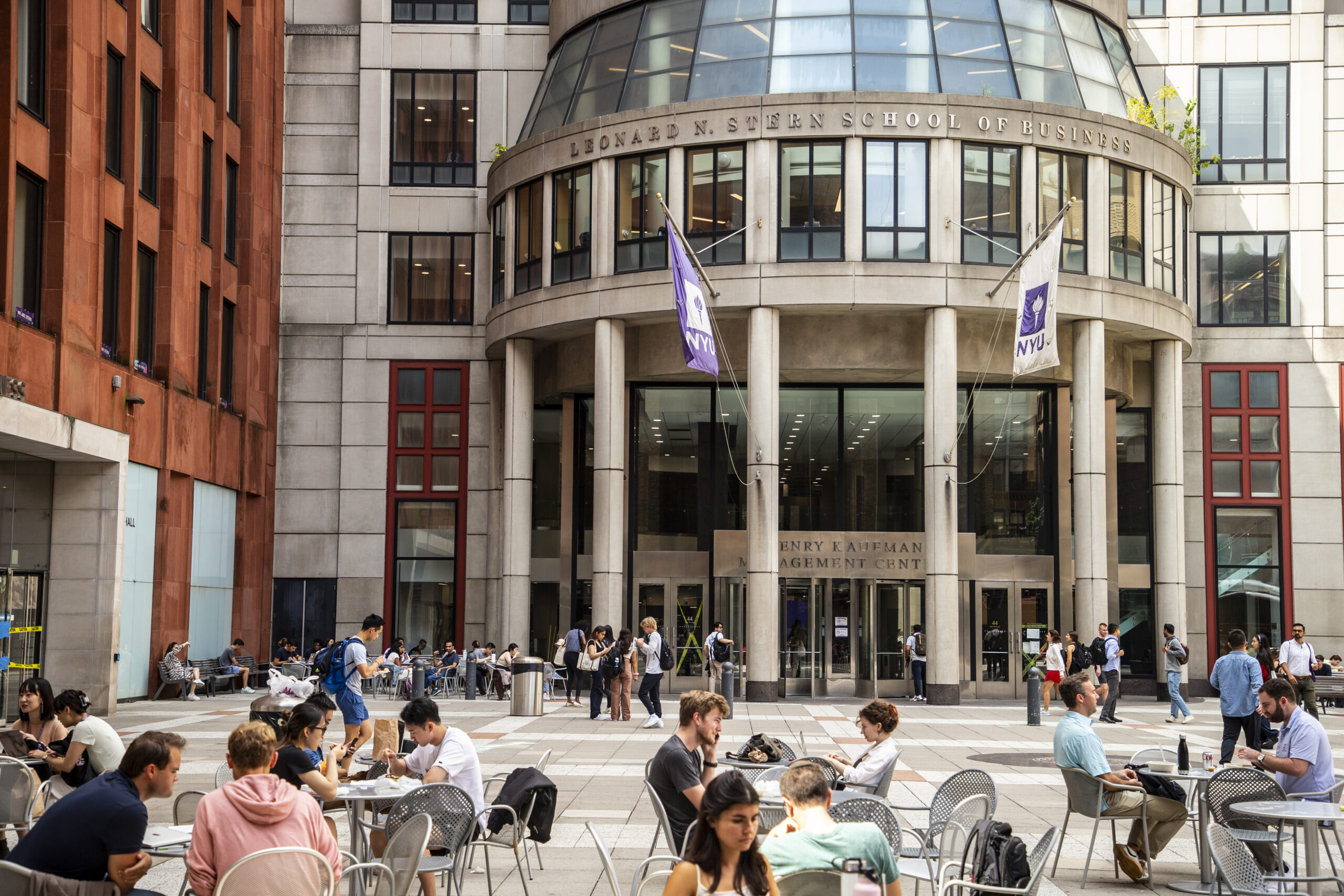 Groups of student seated in front of the NYU Stern School of Business.