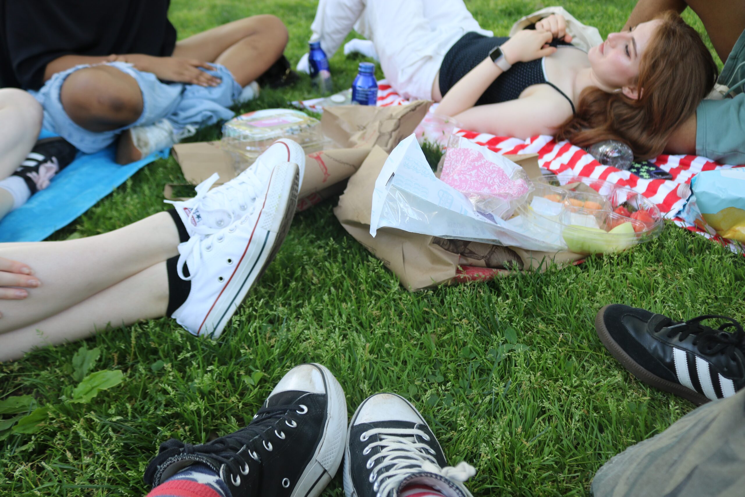 Feet facing pointing to the center of a circle on the grass, with a student lying in the background.