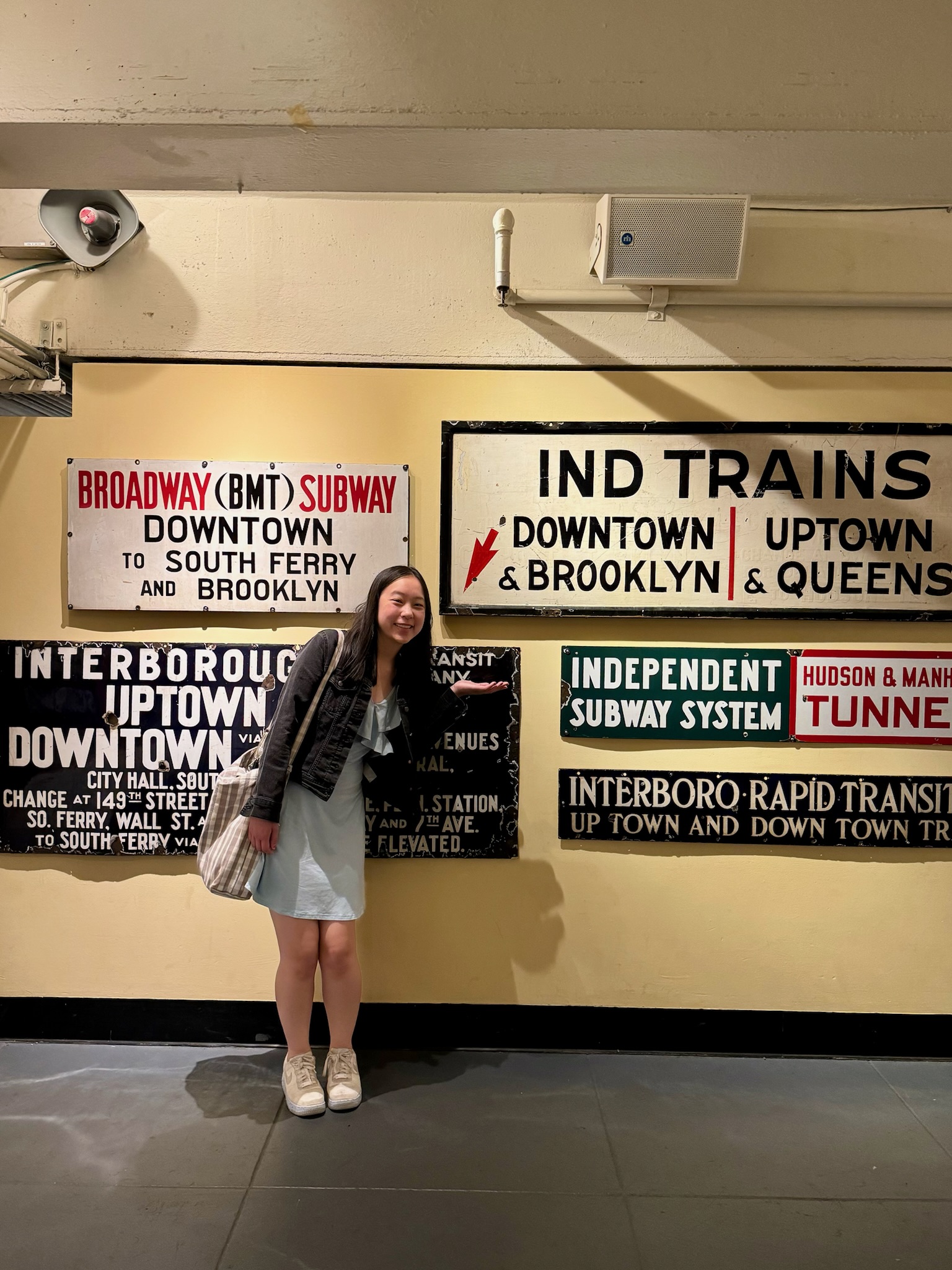 Katy pointing at an old MTA sign directing commuters to 