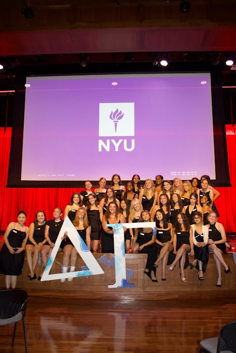 A group of girls holding sorority letters and smiling.