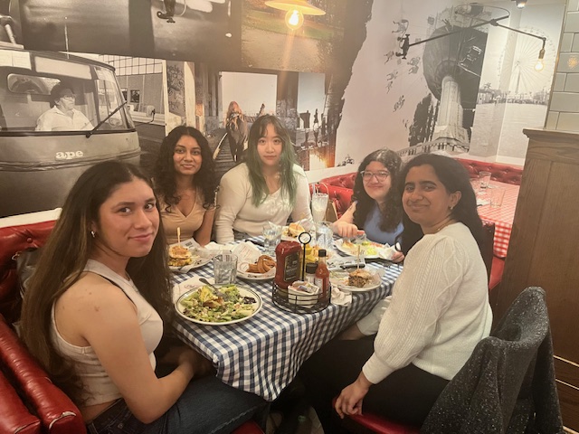 Stutee and 4 friends sit smiling at a table in an NYC restaurant