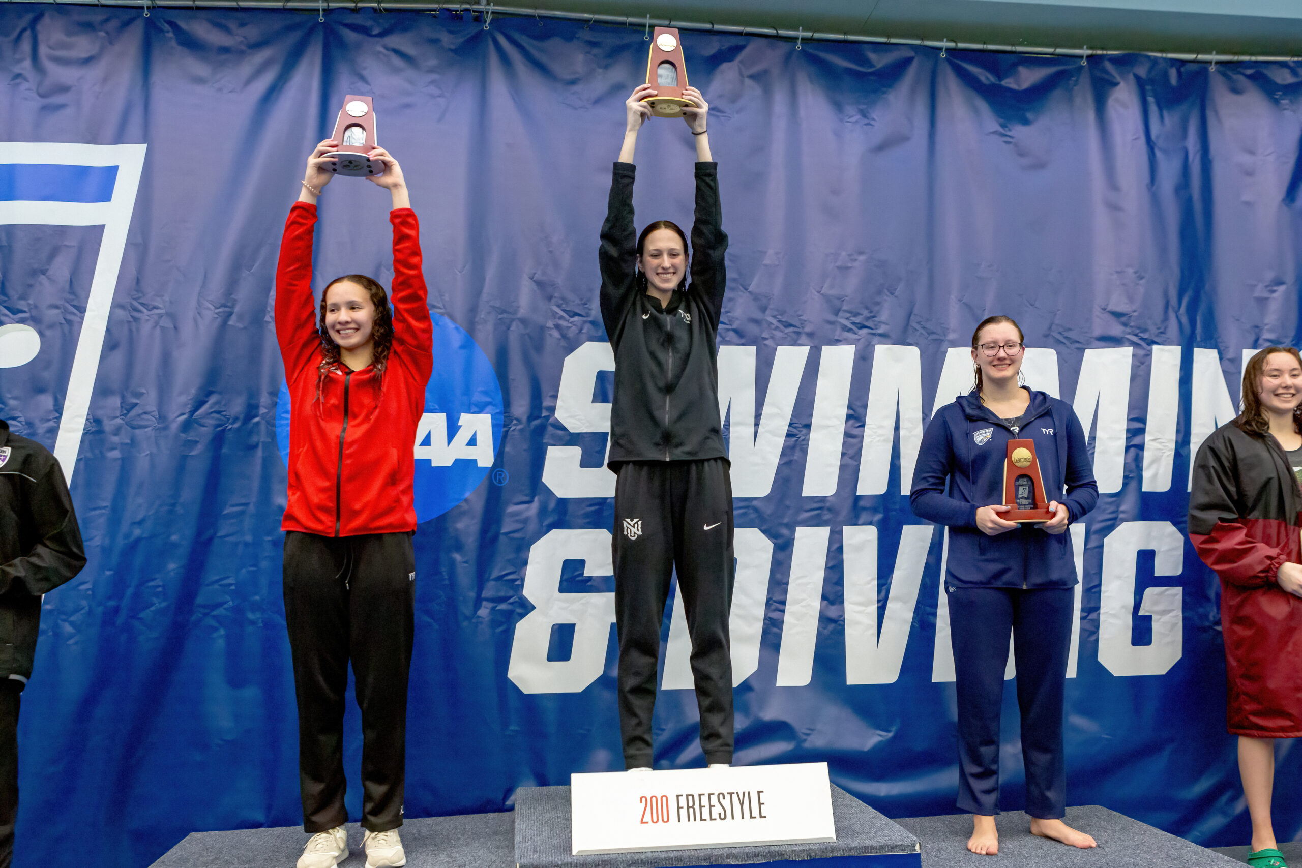 Kaley McIntyre standing on a podium and holding up her award.