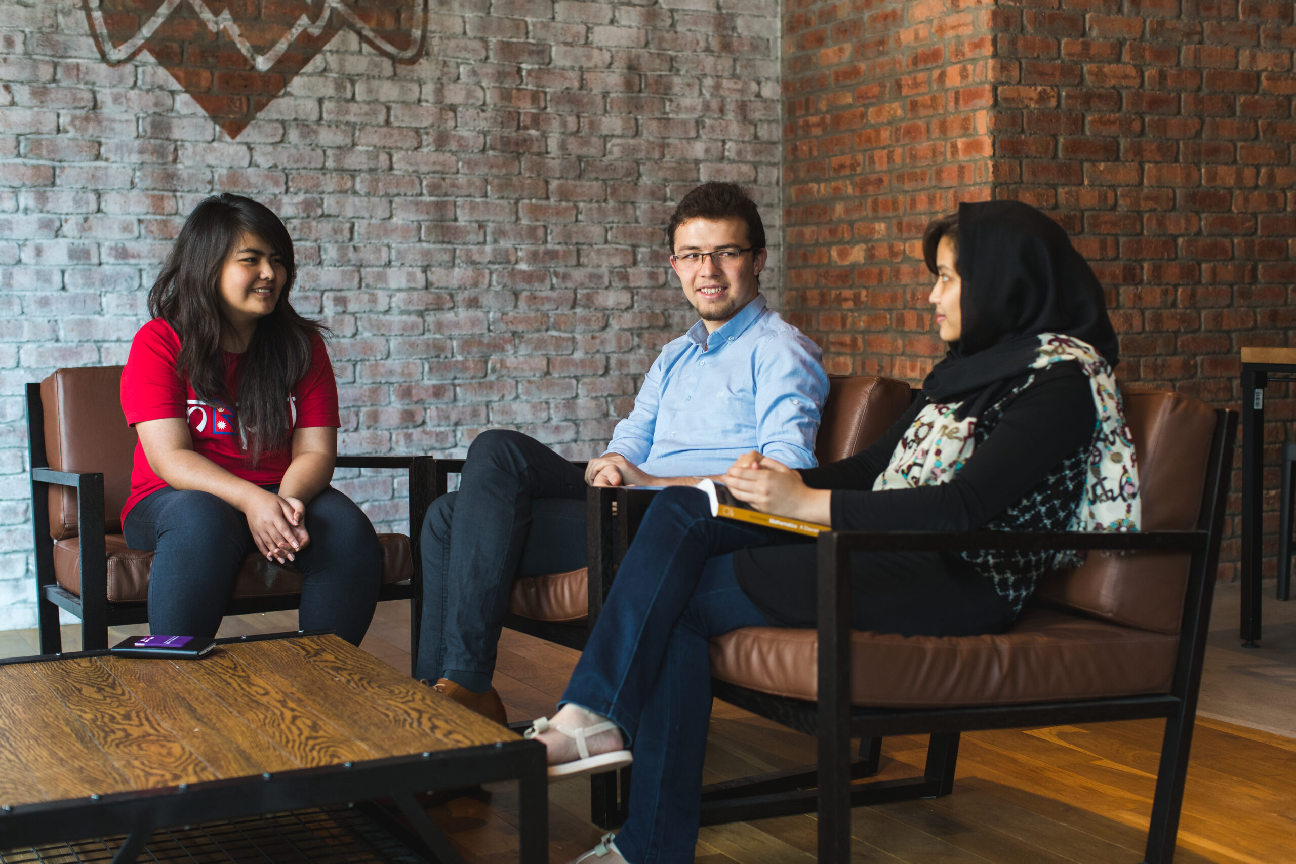 Three students sit and chat together in the Marketplace.