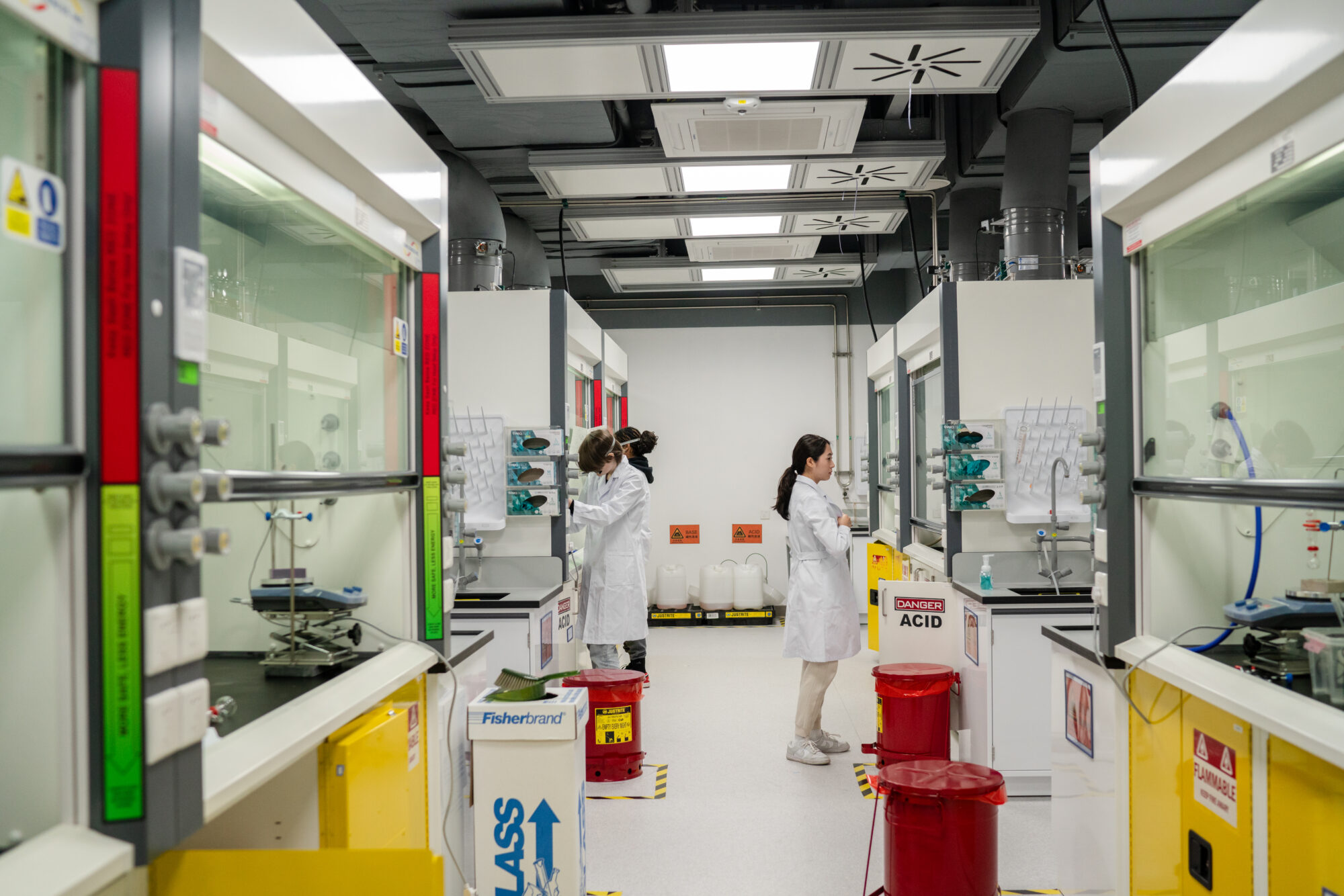 Students working in a lab, wearing white coats.