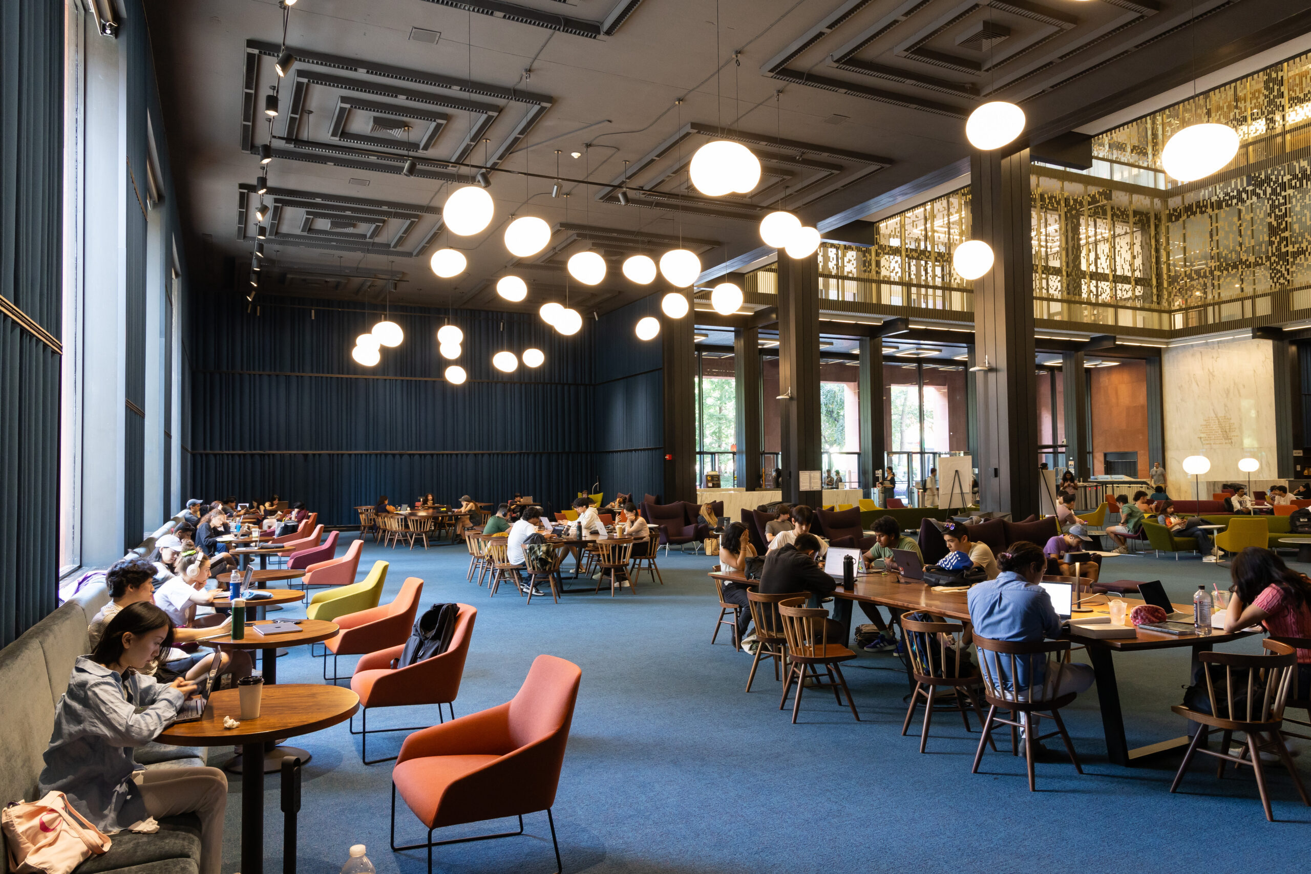 A large hall in Bobst Library, with multiple study spots full of working students.