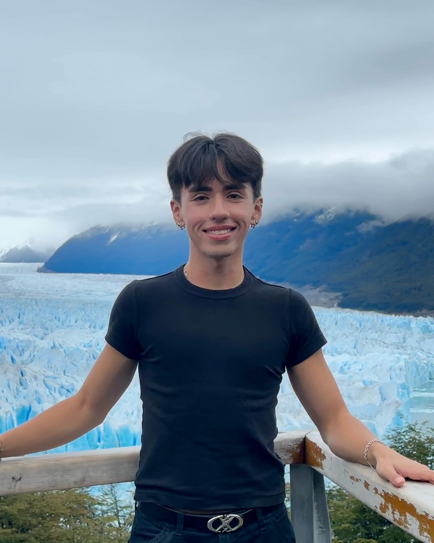 Student Isaac Garcia stands in front of a lake and some mountains.