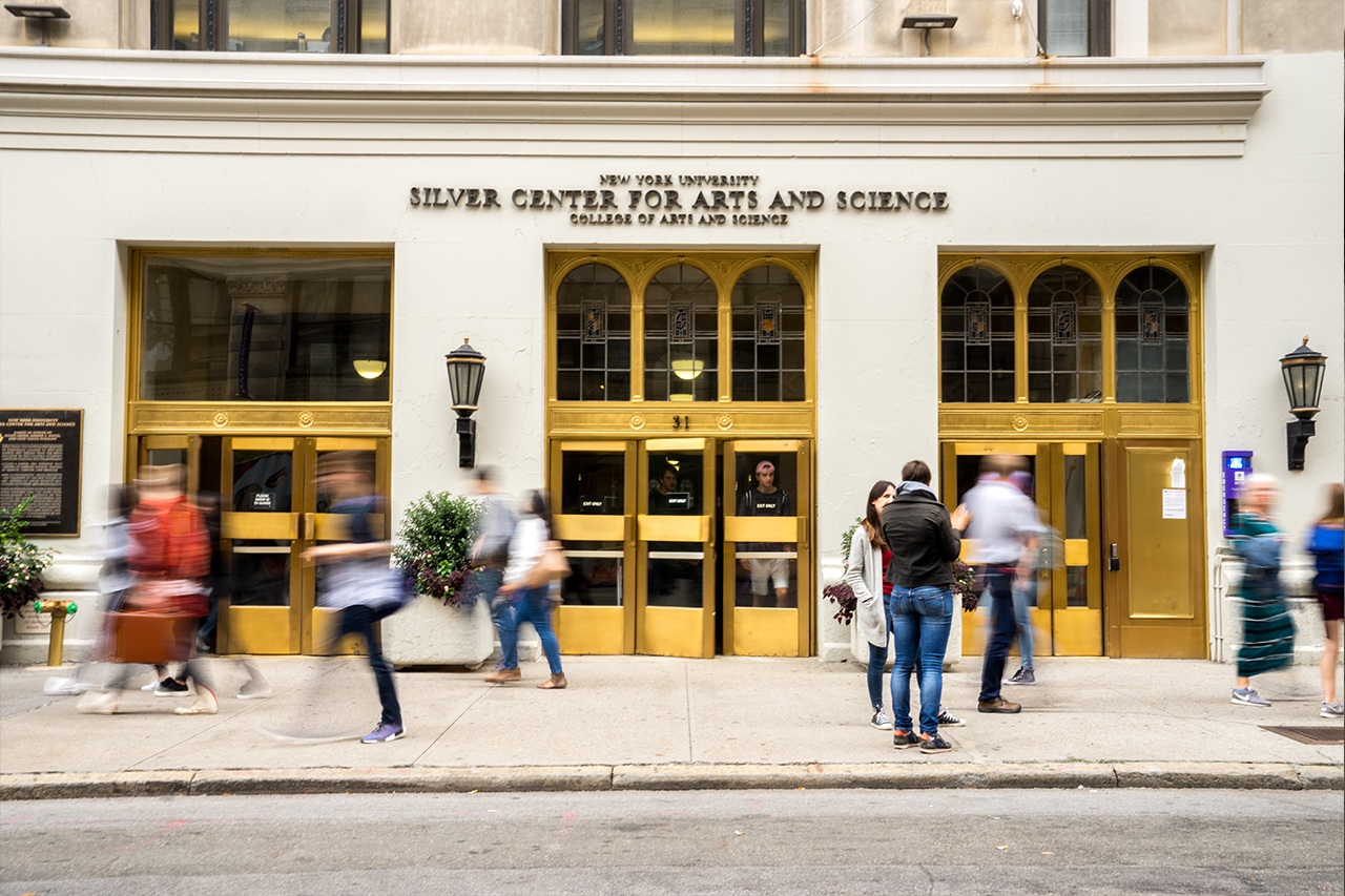 Students walk past and stand in front of the Silver School of Social Work.