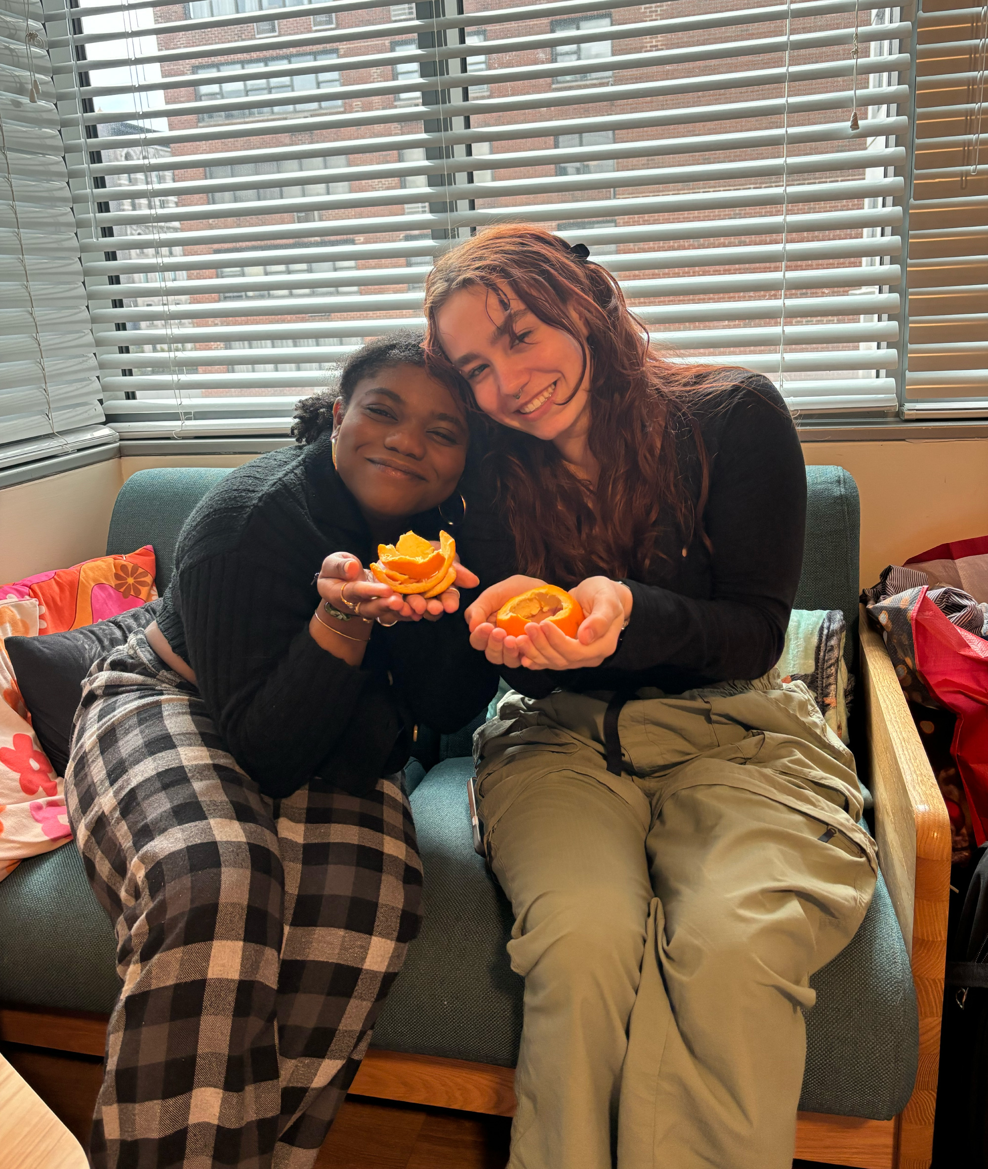 Two students holding peeled oranges during a dorm room event.