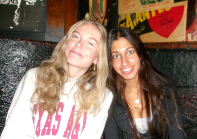 Two girls posing in front of a decorative wall at a restaurant