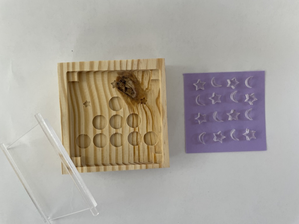 A documentation photo of a tic-tac-toe game variation with a CNC wood board and laser cut acrylic pieces