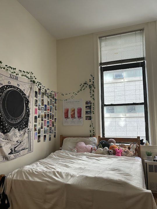 A college dorm with a large bed, many stuffed animals, a picture wall, and a tapestry