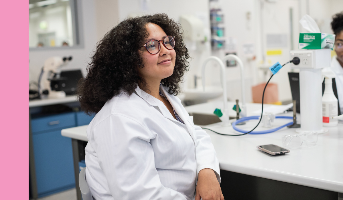 A student in a laboratory setting smiles.