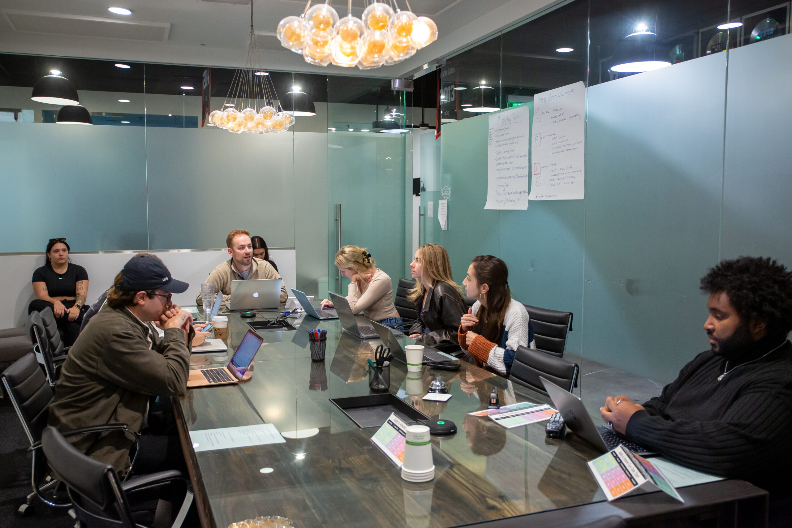 A group of students, laptops out, studying music marketing together in a conference room.