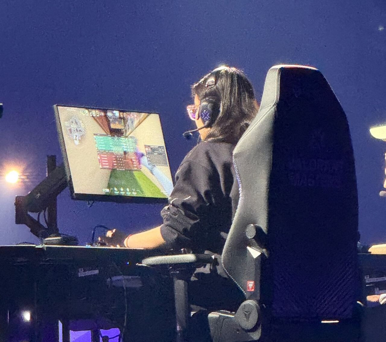 Someone sitting at a gaming computer with a large monitor and wearing a headset.