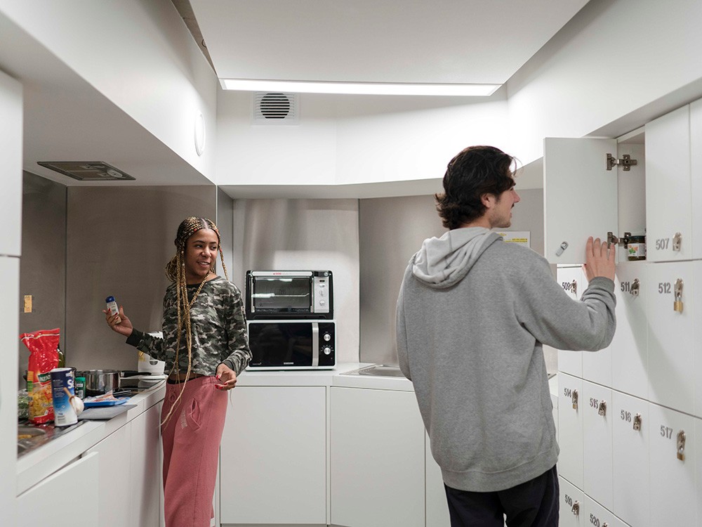 Two students hanging out in a kitchen.