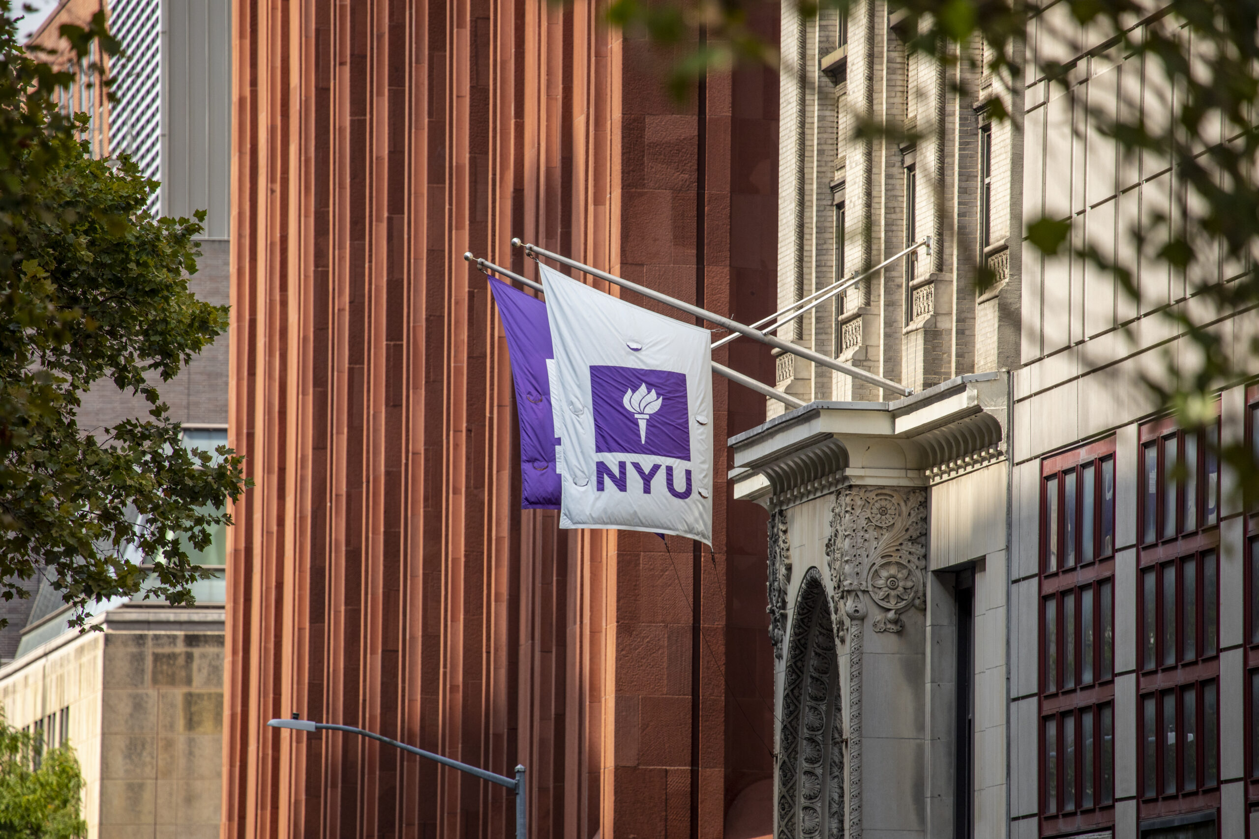 An NYU flag hanging off the side of a building.