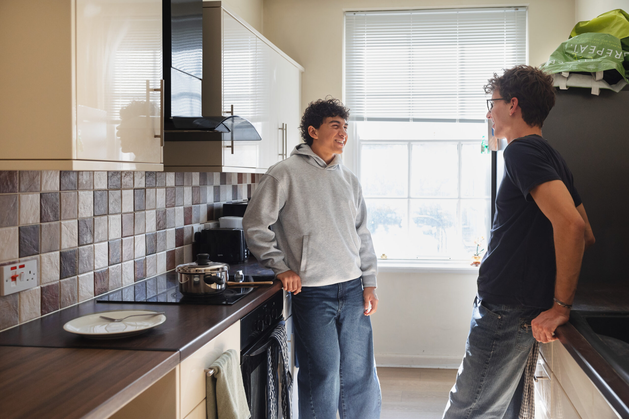 Two students talking in a kitchen.