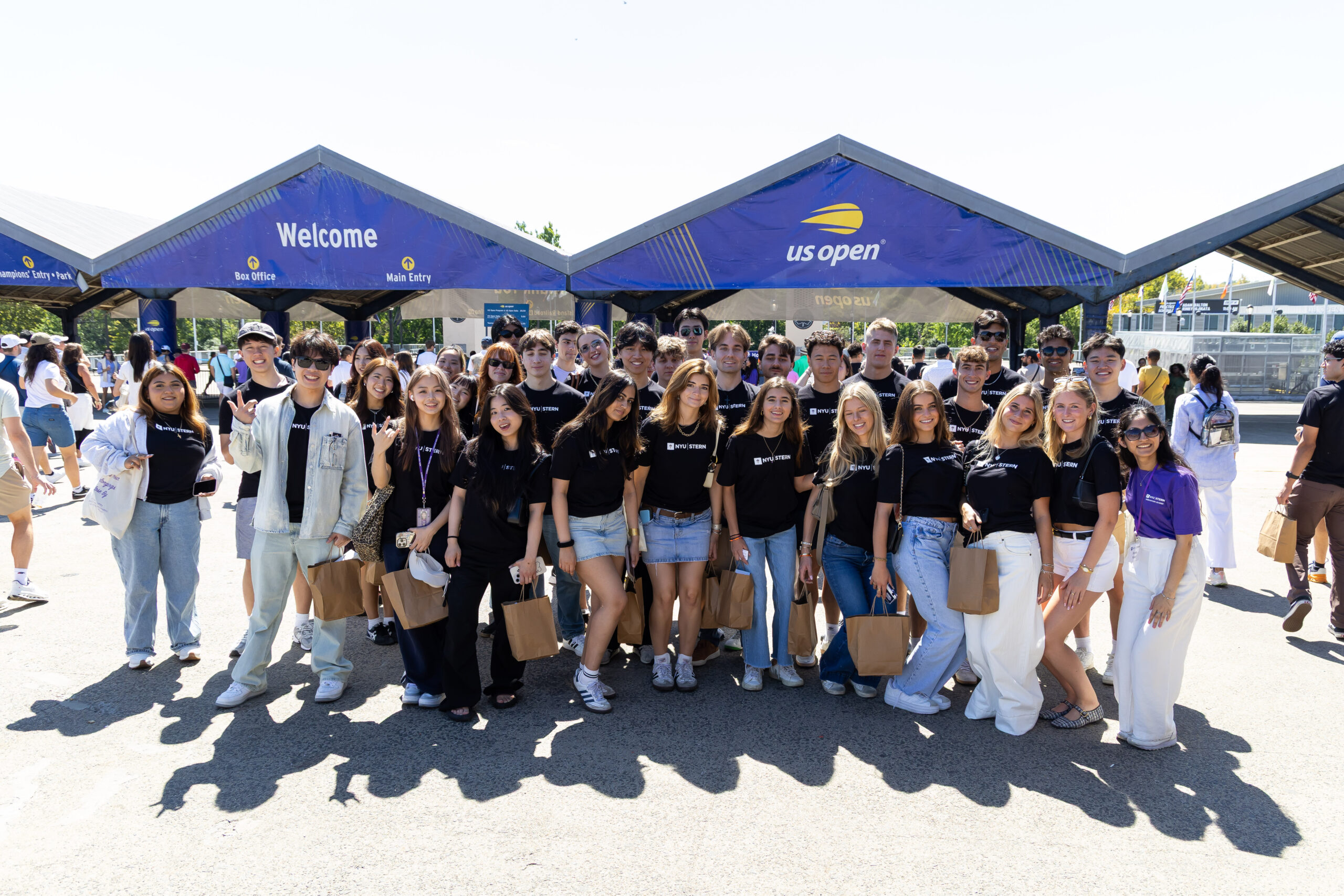 A large group of students posed outside the US Open, wearing black shirts that read ”NYU Stern.”