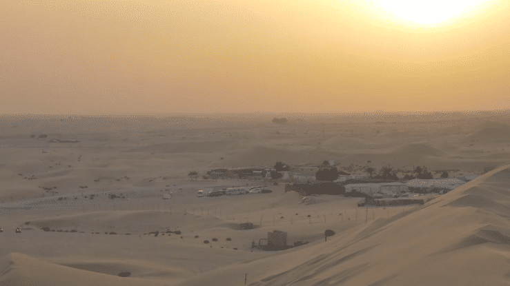 A GIF of students seated on sand dunes during a class outing.