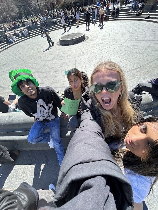 Four friends dressed as leprechauns outside with signs about raising money for childhood cancer.