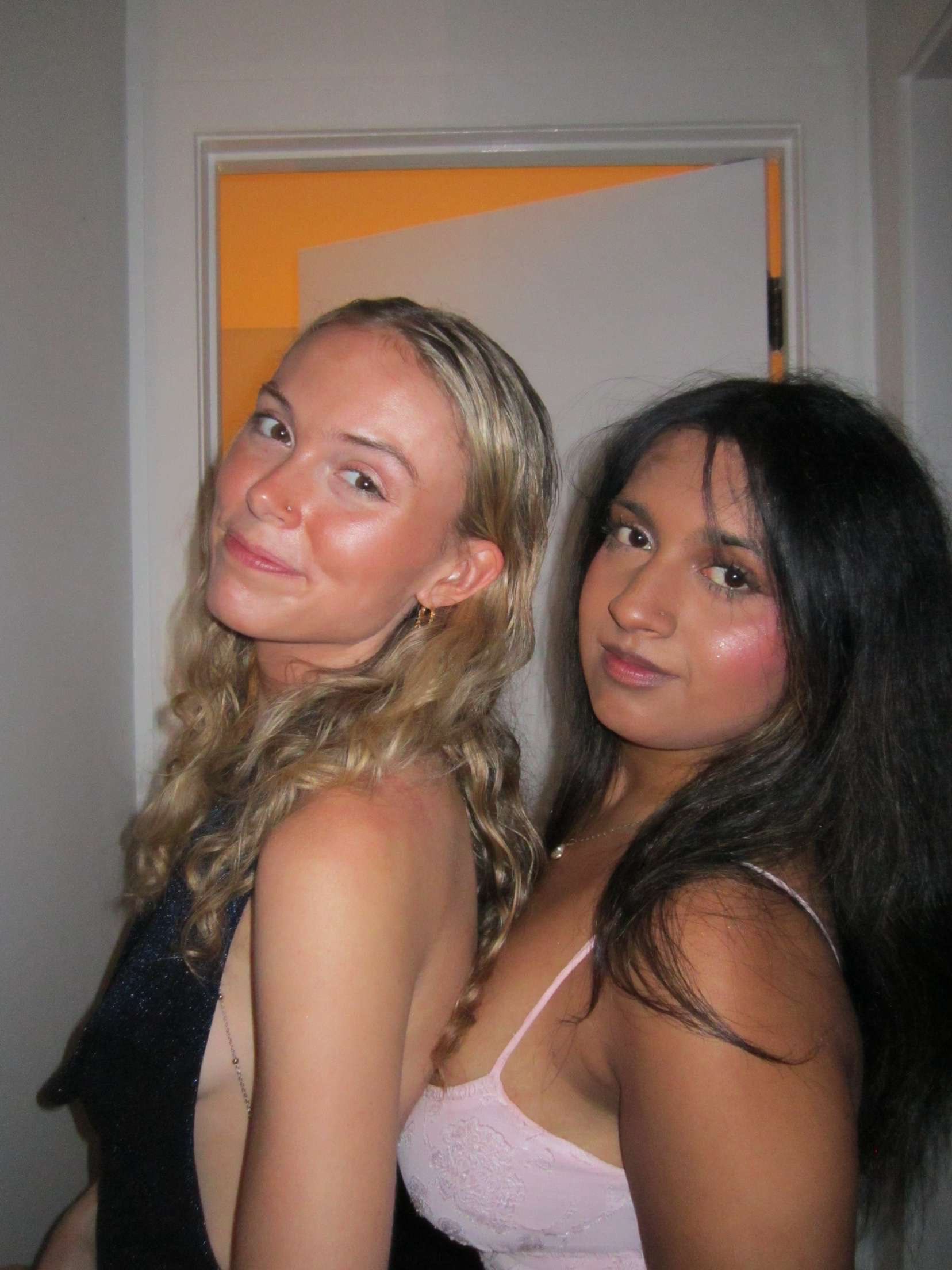 Two girls in formal dresses getting ready for a sorority formal.