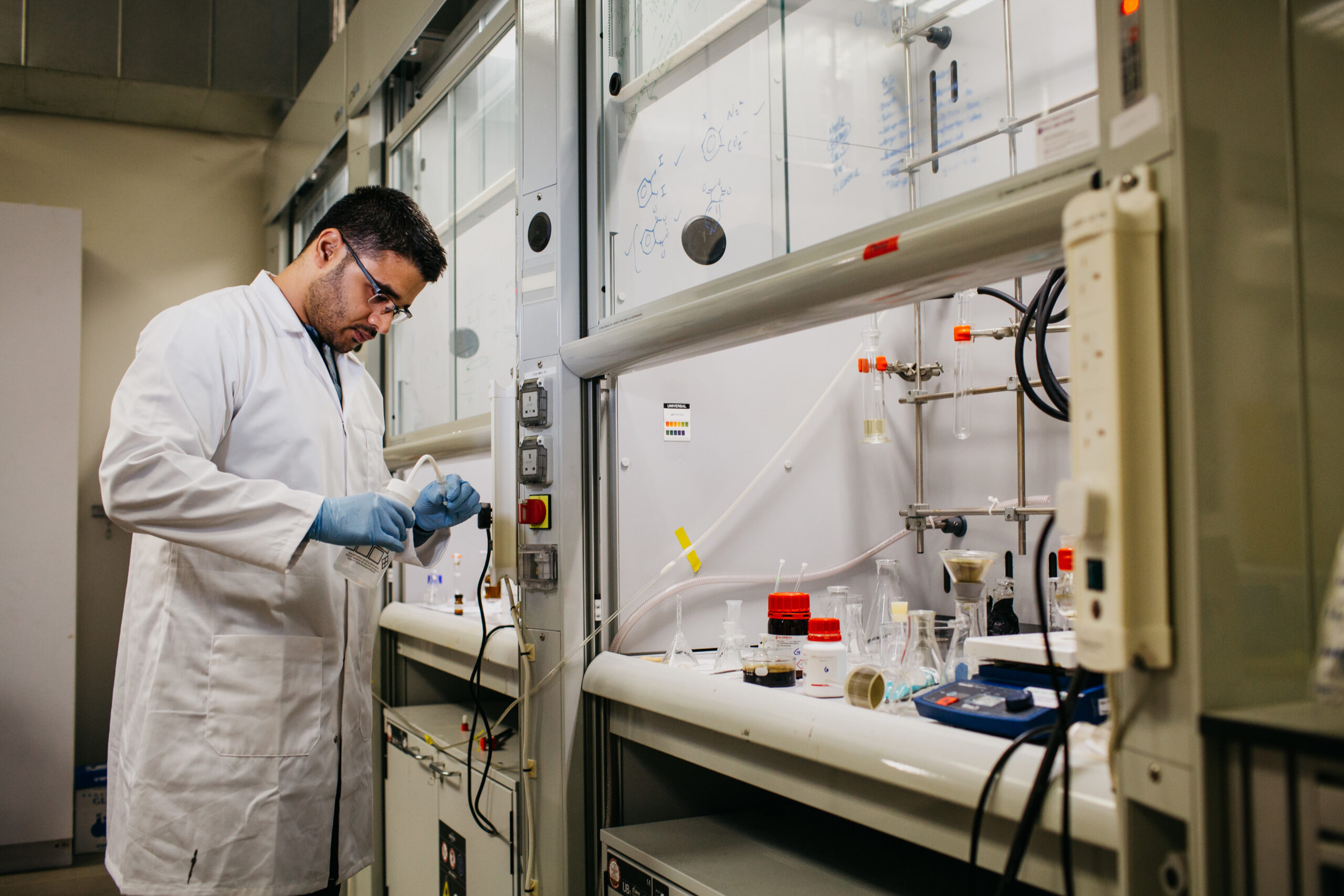 A student works in a lab with a white coat on.