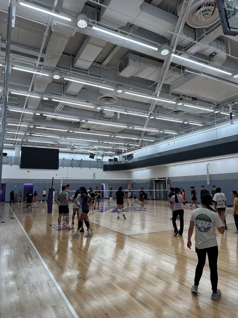 People on either side of a volleyball court as a game is in progress.