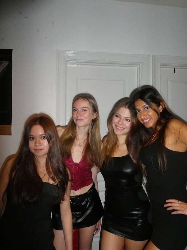 Four girls wearing dresses & skirts pose together and smile for the camera.