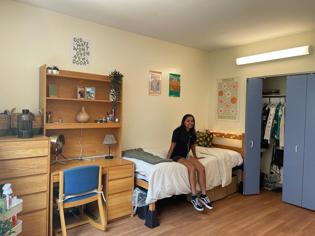 College student sitting on a dorm bed on move-in day, freshman year