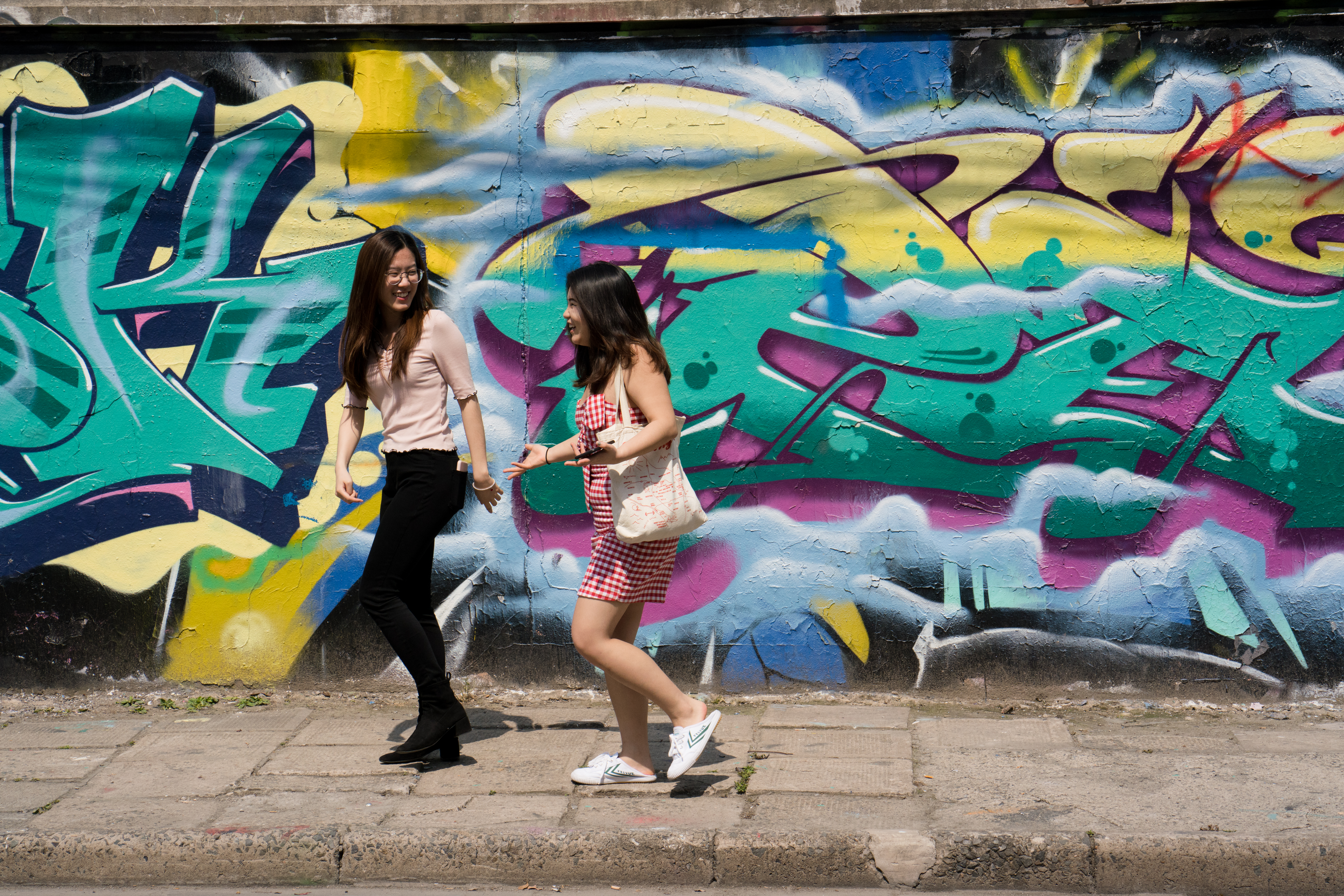 Two students walk by a graffiti wall in Shanghai.