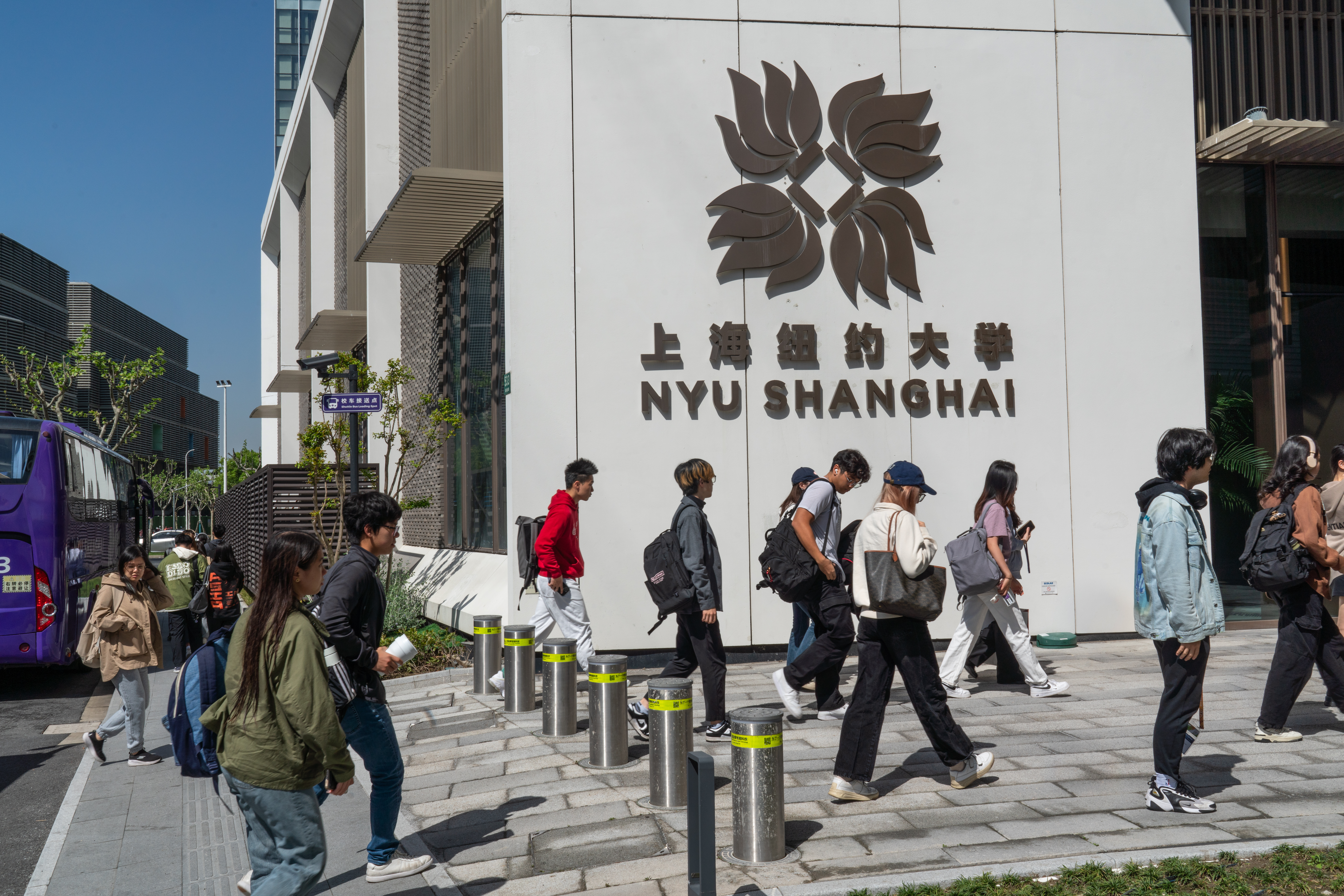 A large group of students walking through the entrance of the NYU Shanghai campus.