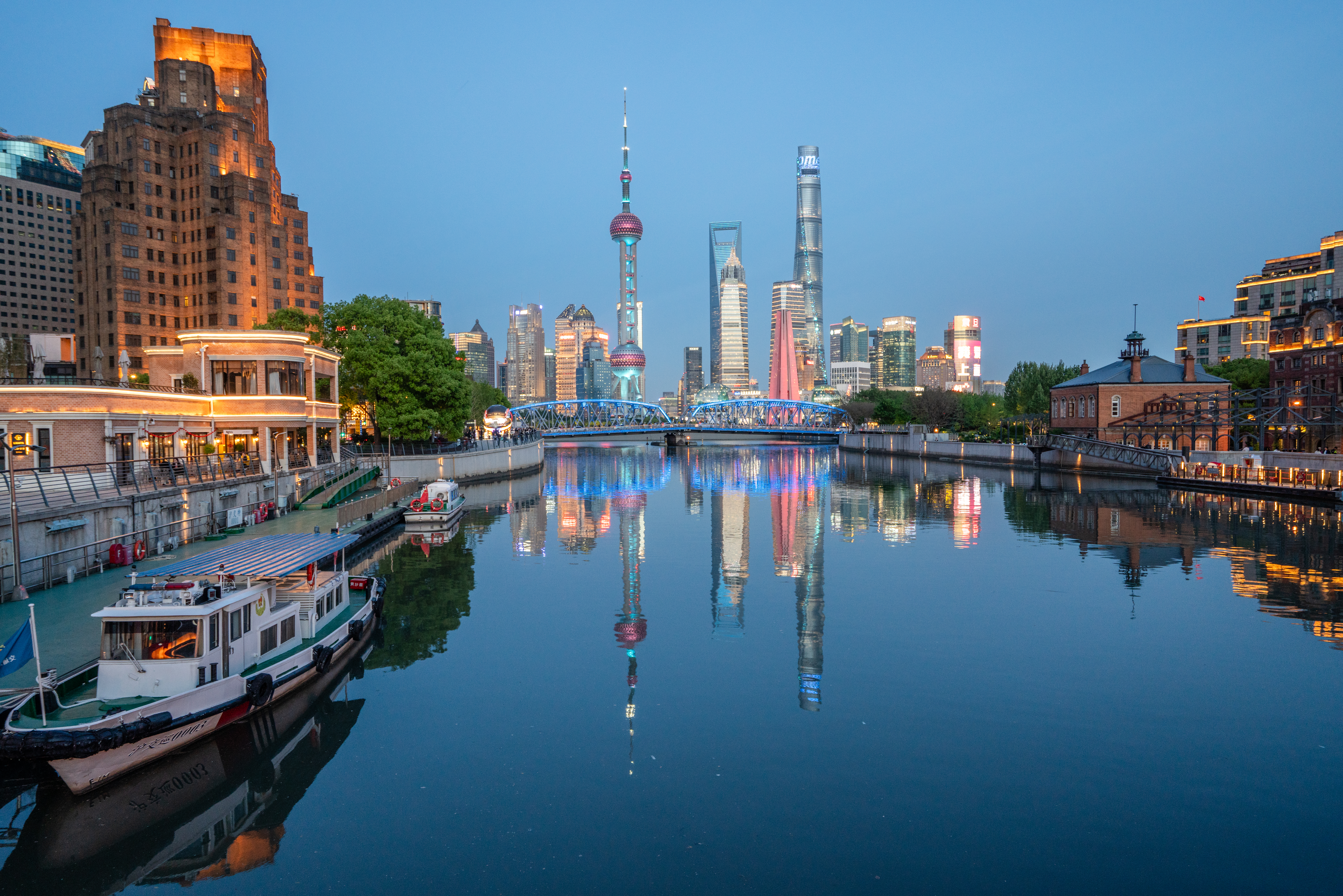 The Shanghai skyline, illuminated against a deep blue sky.